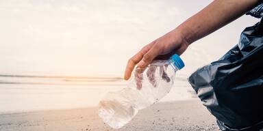 Beachcleaning Mann hebt Plastikflasche auf