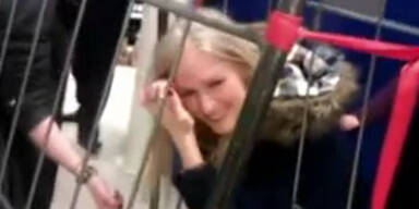 Frau steckt mit Kopf in Gitter fest