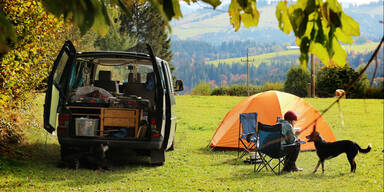 Frau beim Camping mit Hund und Van