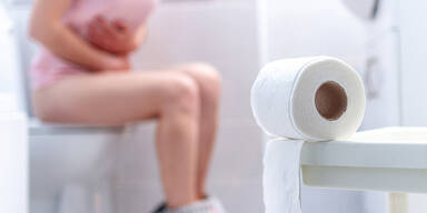 Frau mit Schmerzen auf der Toilette