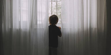 Junge schaut aus dem Fenster