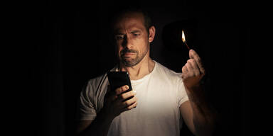 Blackout: Mann mit Streichholz im Dunkeln