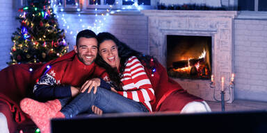 Mann und Frau zu Weihnachten vor dem Fernseher