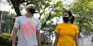 Menschen mit Maske beim Spazieren im Freien