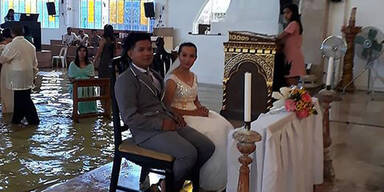 Braut watet durch überflutete Kirche zu Altar