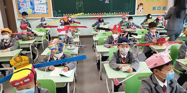 Kinder tragen "Ein-Meter-Hüte" in chinesischer Volksschule